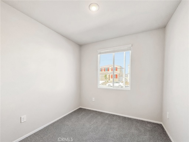 carpeted spare room featuring baseboards