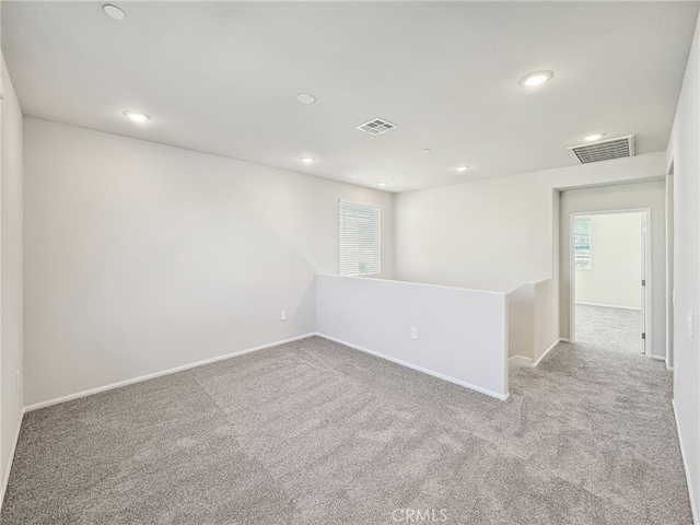 carpeted empty room featuring visible vents and recessed lighting