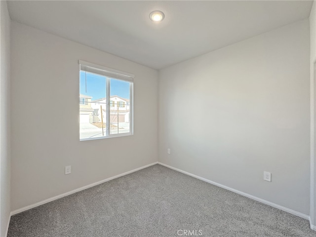 carpeted spare room featuring baseboards