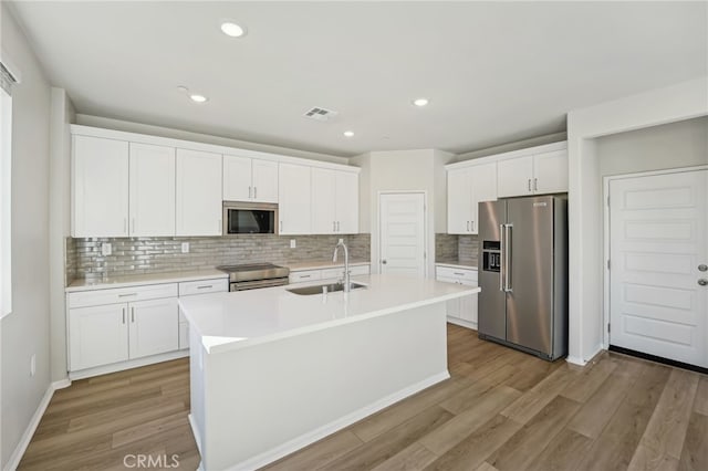 kitchen featuring stainless steel appliances, visible vents, a sink, and light wood finished floors