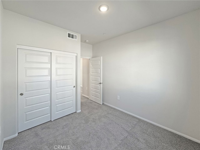 unfurnished bedroom with a closet, carpet flooring, visible vents, and baseboards