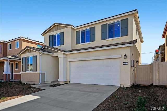 traditional-style home featuring concrete driveway, fence, an attached garage, and stucco siding