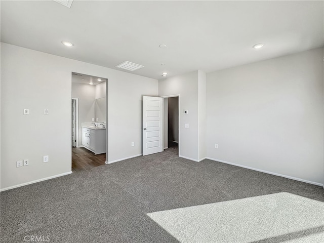 unfurnished bedroom featuring visible vents, baseboards, dark colored carpet, a sink, and recessed lighting