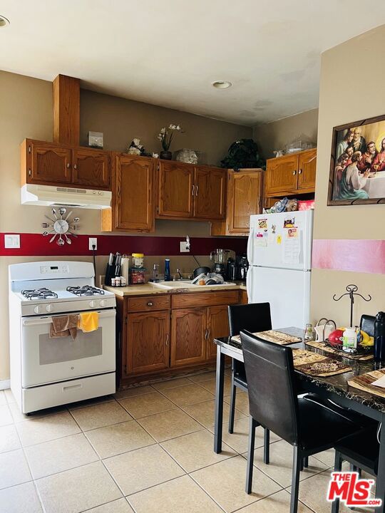 kitchen with light tile patterned flooring, white appliances, and sink