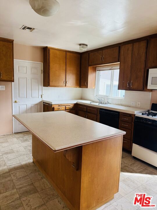 kitchen with a breakfast bar, tasteful backsplash, a center island, dishwasher, and stove