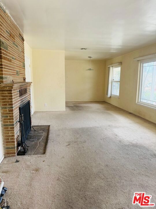 unfurnished living room featuring light colored carpet and a fireplace