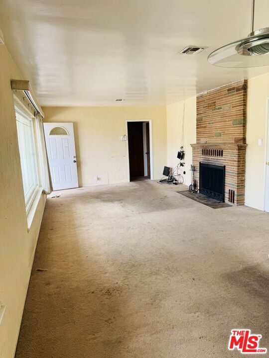 unfurnished living room with carpet and a fireplace