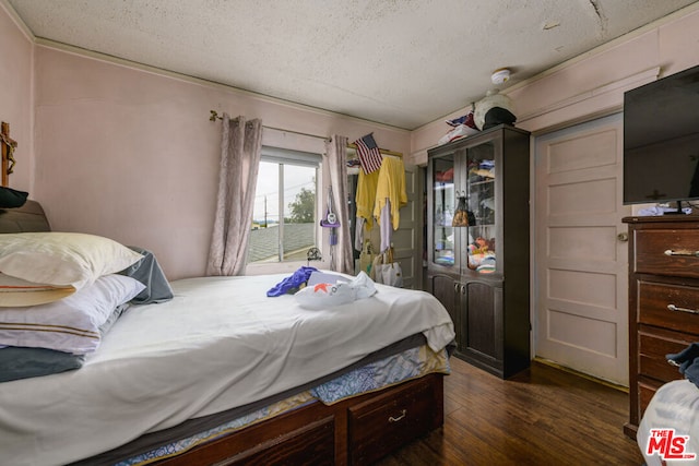 bedroom with access to exterior, dark wood-type flooring, and a textured ceiling