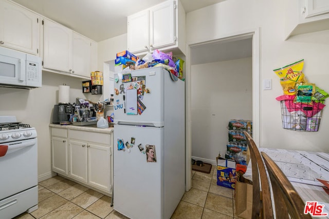 kitchen with white cabinetry, white appliances, and light tile patterned flooring