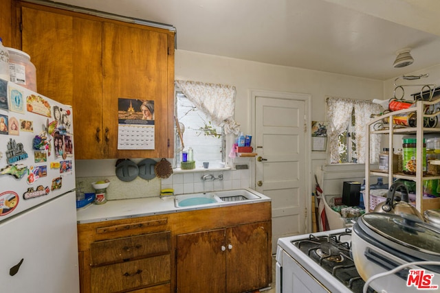 kitchen with tasteful backsplash, white appliances, and sink