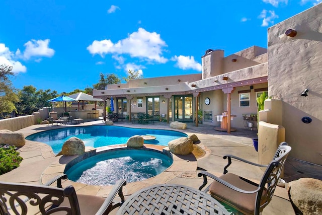 view of swimming pool with a pool with connected hot tub, a patio, and fence