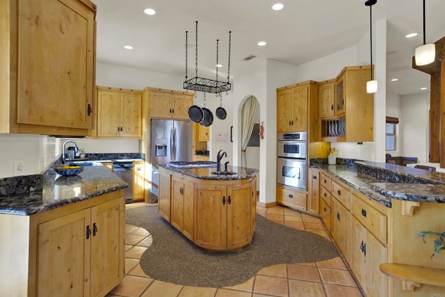 kitchen with visible vents, a sink, dark stone countertops, stainless steel appliances, and arched walkways