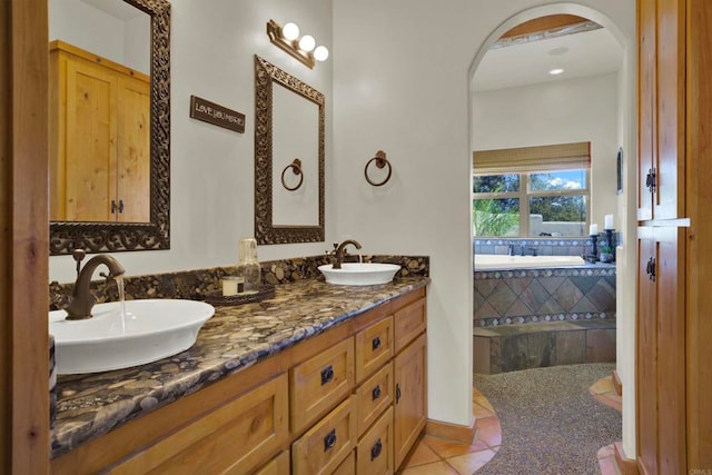 bathroom with tile patterned flooring, double vanity, a bath, and a sink