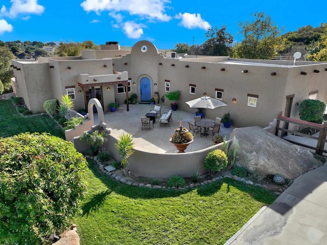 back of house with a patio, a lawn, and stucco siding