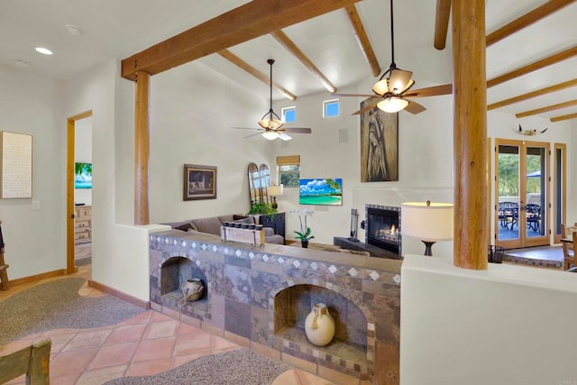 living area with tile patterned flooring, ceiling fan, baseboards, beamed ceiling, and a glass covered fireplace