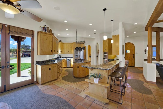 kitchen with arched walkways, recessed lighting, pendant lighting, and a center island