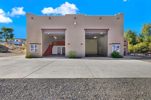 rear view of house featuring french doors, driveway, and stucco siding