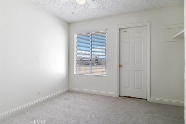 carpeted spare room featuring ceiling fan and a textured ceiling