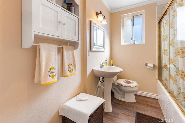 full bathroom with sink, crown molding, hardwood / wood-style floors, bath / shower combo with glass door, and toilet