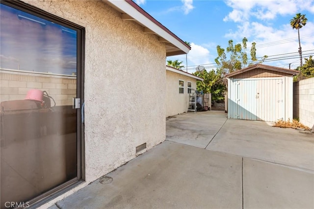 view of side of property with a patio and a storage shed