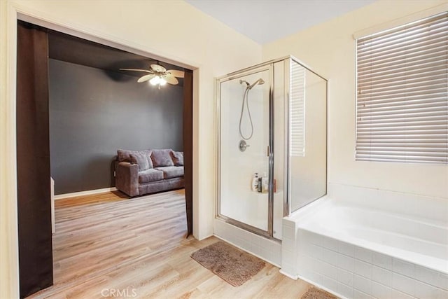 full bath featuring a stall shower, ceiling fan, a bath, and wood finished floors