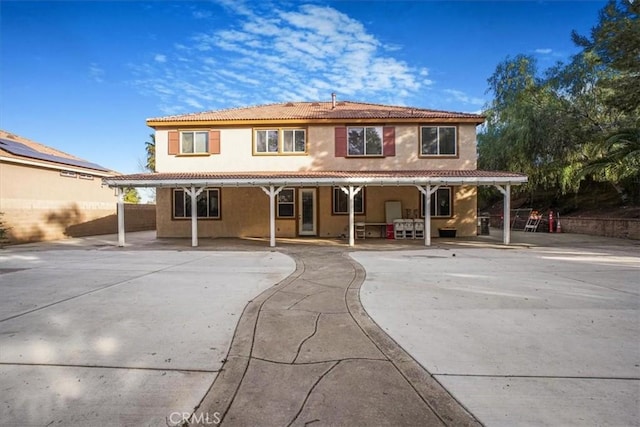 back of house featuring a tile roof, a patio area, and stucco siding