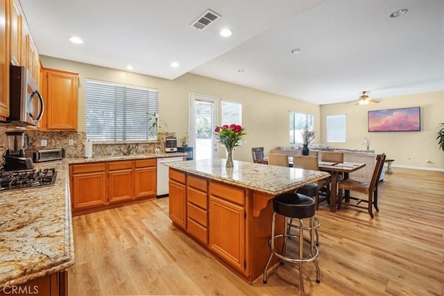 kitchen featuring a center island, visible vents, appliances with stainless steel finishes, light wood-type flooring, and a kitchen breakfast bar