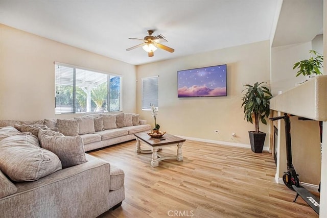 living room featuring ceiling fan, light wood-type flooring, and baseboards