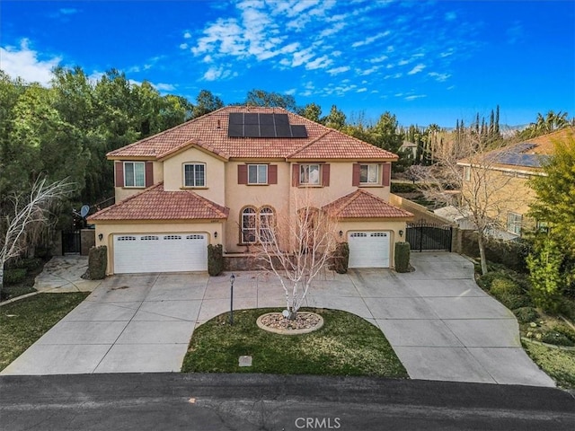 mediterranean / spanish home with stucco siding, concrete driveway, a gate, fence, and a tiled roof