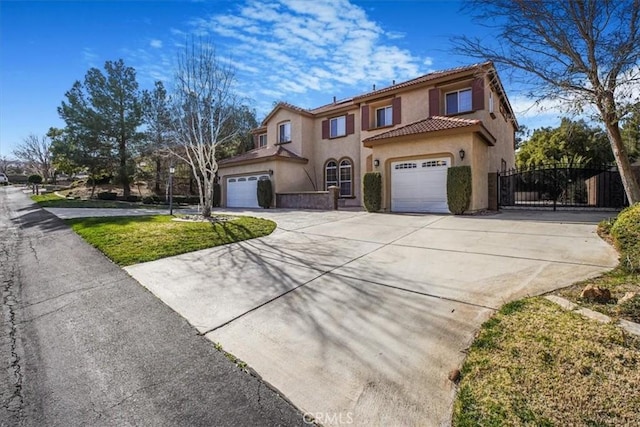 mediterranean / spanish-style house with an attached garage, a tile roof, driveway, a gate, and stucco siding