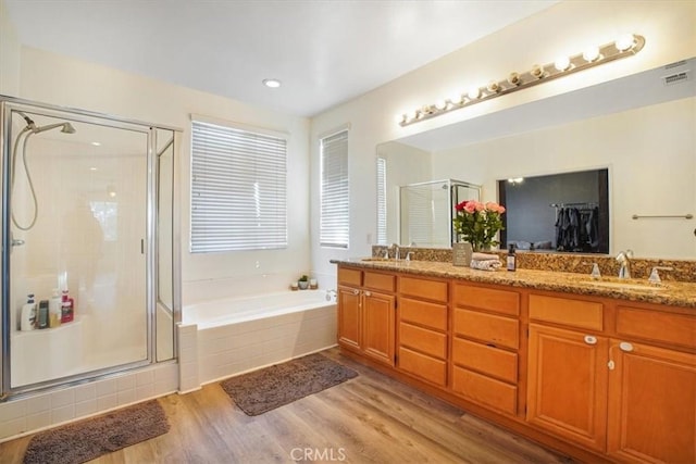 bathroom with double vanity, a shower stall, a sink, and wood finished floors