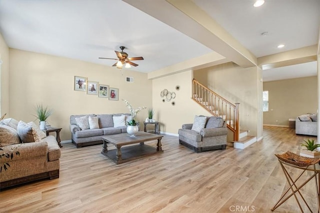 living room with baseboards, visible vents, a ceiling fan, light wood-style flooring, and stairs