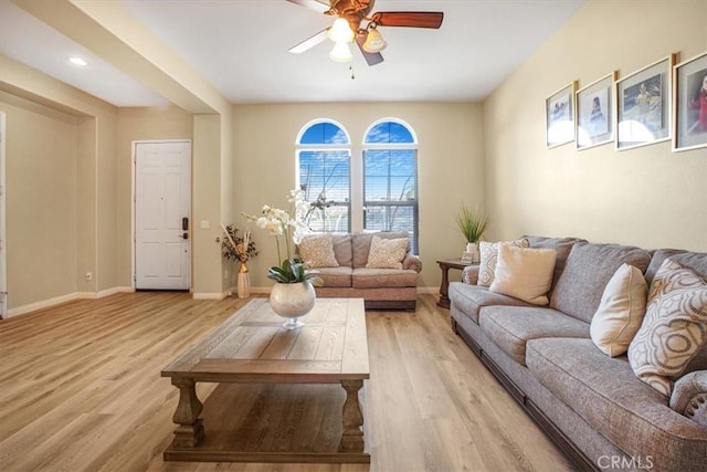 living room featuring light wood-type flooring, a ceiling fan, and baseboards