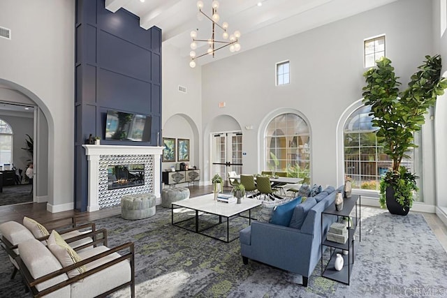 living room featuring a fireplace, hardwood / wood-style floors, a high ceiling, and a notable chandelier