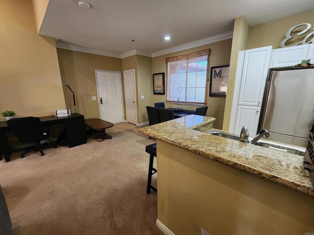 kitchen featuring white cabinetry, ornamental molding, light stone countertops, and a kitchen breakfast bar