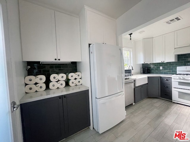 kitchen featuring sink, backsplash, white cabinets, white appliances, and light hardwood / wood-style flooring