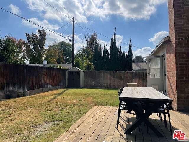 deck with a storage shed and a lawn