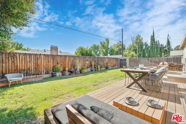 wooden deck with a shed and a lawn