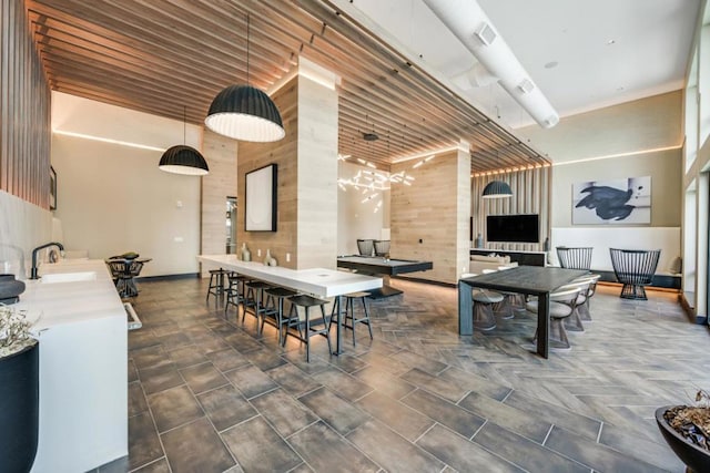 dining space featuring sink, a high ceiling, and wood walls