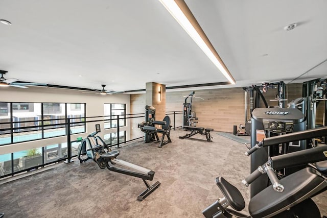 workout area featuring ceiling fan and wooden walls