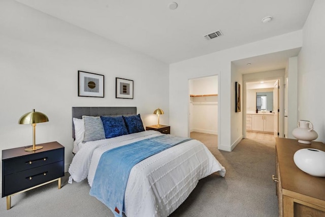 bedroom with light carpet, a walk in closet, and a closet