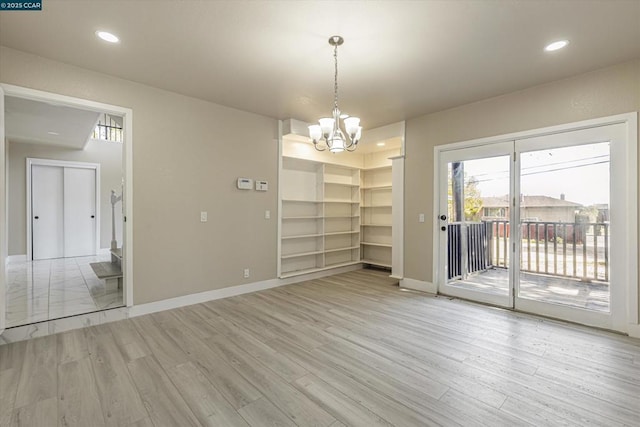 unfurnished dining area with light hardwood / wood-style flooring and a notable chandelier