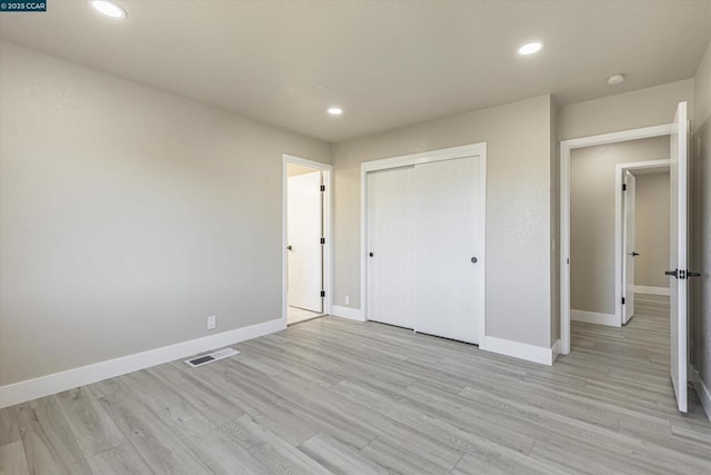 unfurnished bedroom featuring light wood-type flooring and a closet