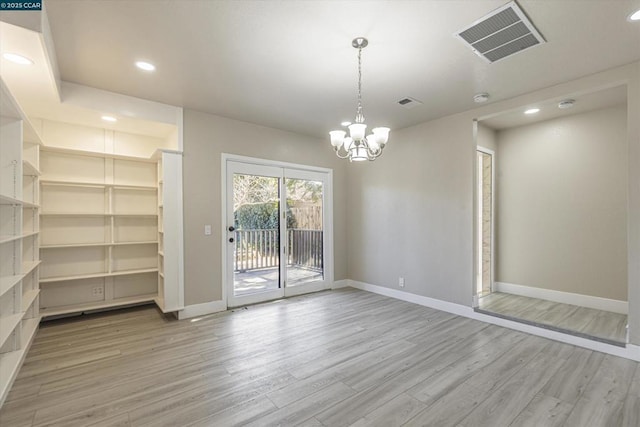 unfurnished dining area with wood-type flooring and a chandelier