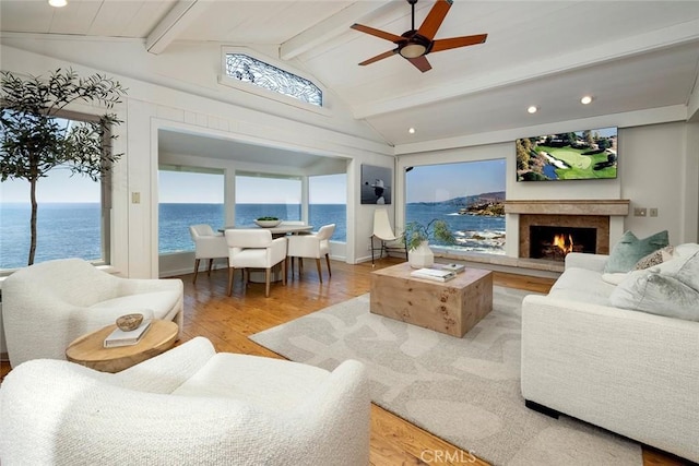 living room with a water view, wood-type flooring, lofted ceiling with beams, and a wealth of natural light