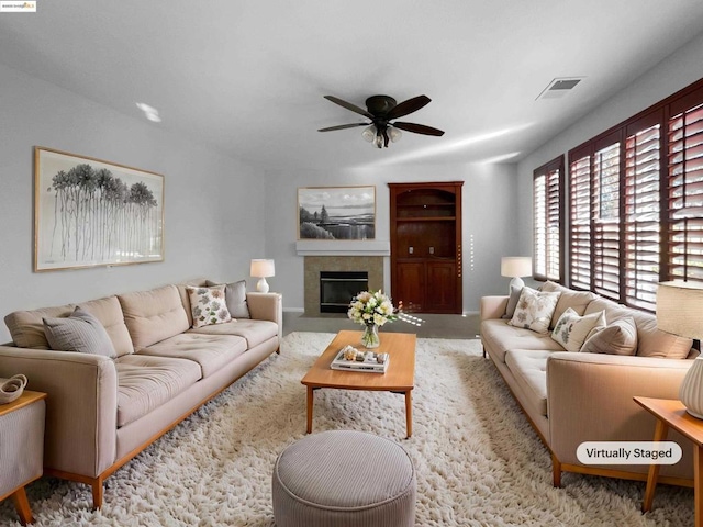 carpeted living room featuring a tile fireplace and ceiling fan