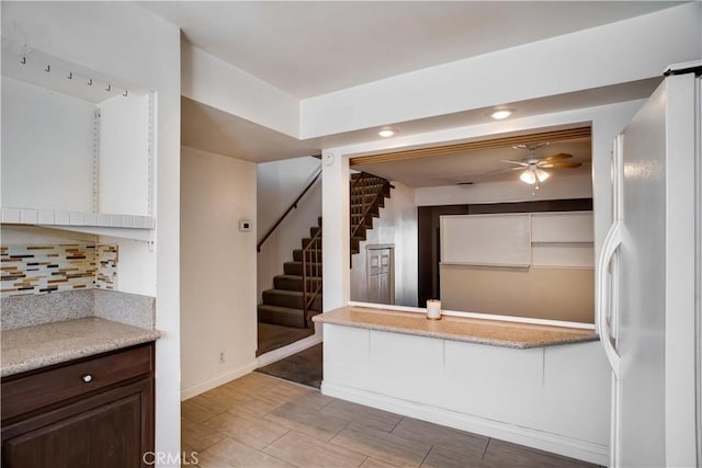 kitchen with decorative backsplash, dark brown cabinets, ceiling fan, and white fridge