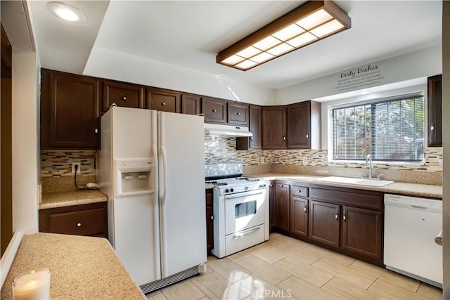 kitchen with dark brown cabinetry, sink, backsplash, and white appliances