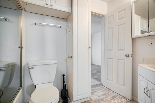 full bathroom featuring toilet, vanity, and bath / shower combo with glass door