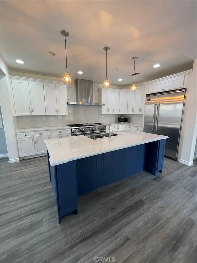 kitchen featuring white cabinets, high quality appliances, hanging light fixtures, and wall chimney range hood